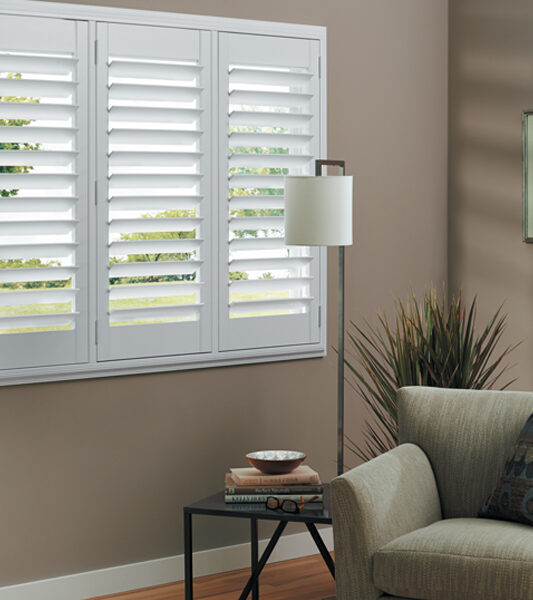 green chair in neutral living room with plantation shutters child-safe blinds by hunter douglas Remp 89520