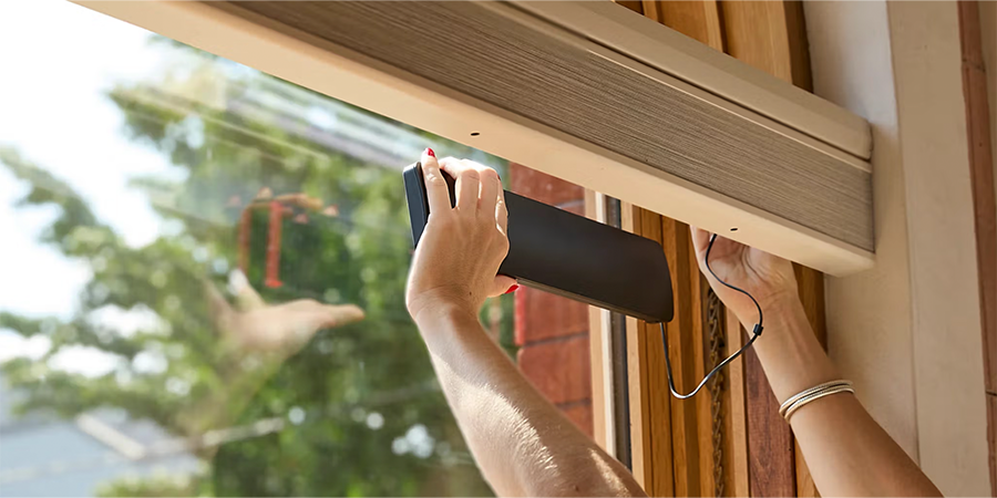 PowerView® solar charger being installed inside the window, wired to the rechargeable battery wand for continual charging