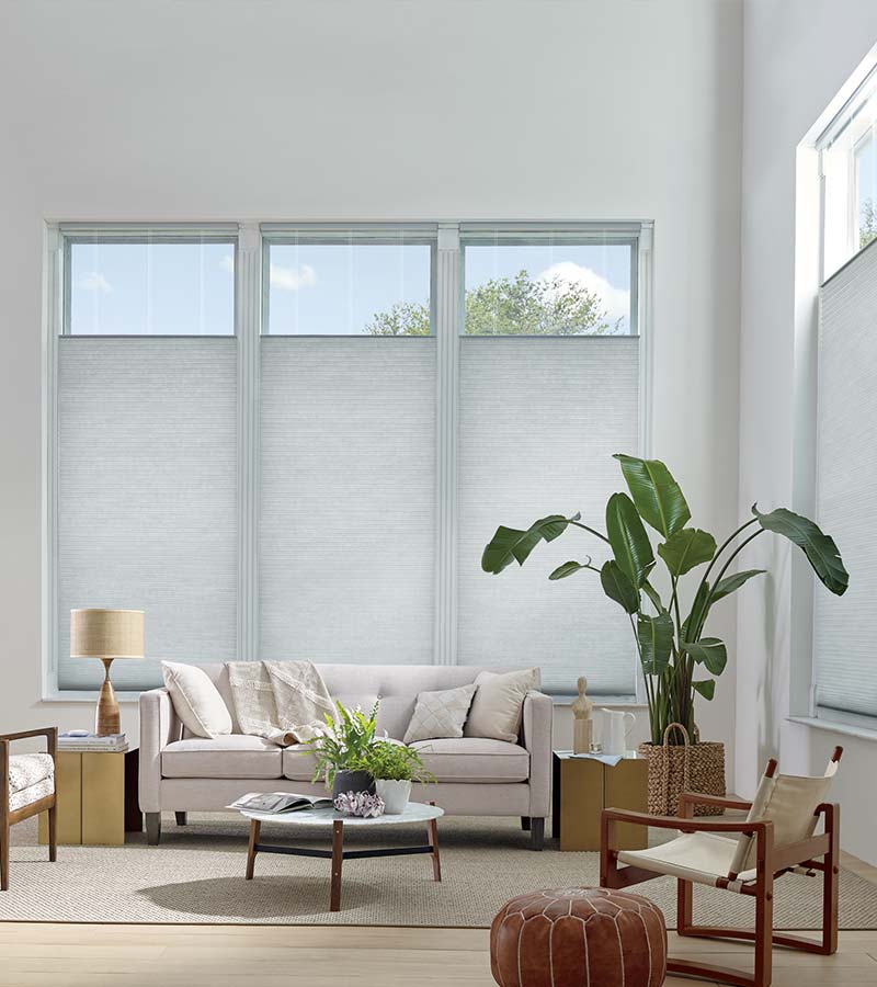 contemporary white living room with honeycomb shades on tall windows in Reno NV for window covering solutions