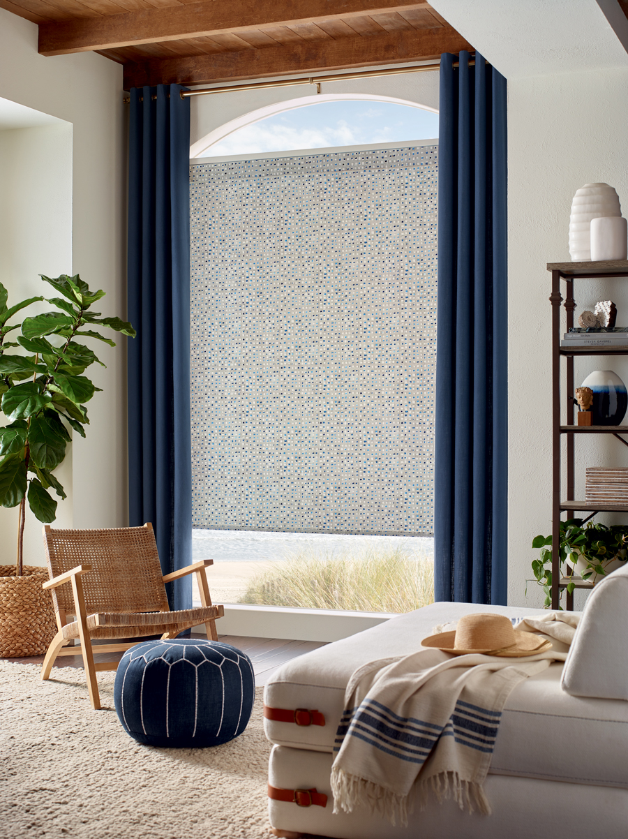 coastal living room area with blue floor to ceiling ripple fold drapery and designer screen shades