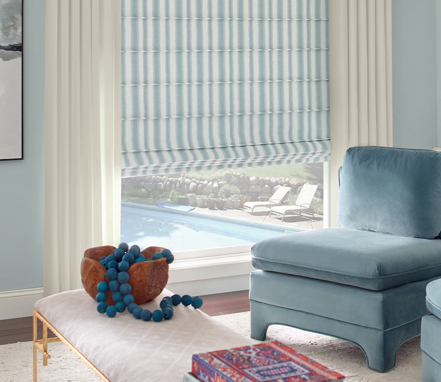 modern living room with plush blue velvet chair and drapes with blue and white stripes