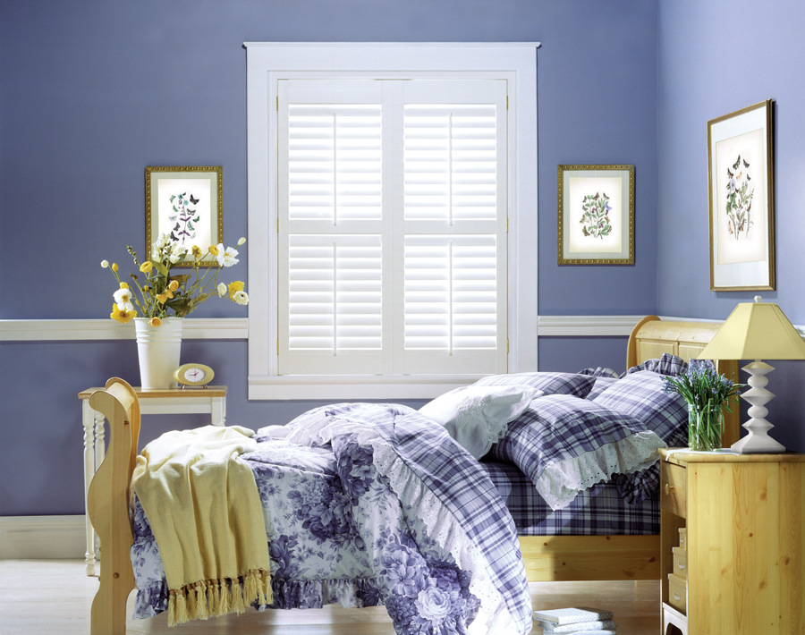 white plantation shutters next to periwinkle wall color in girls bedroom