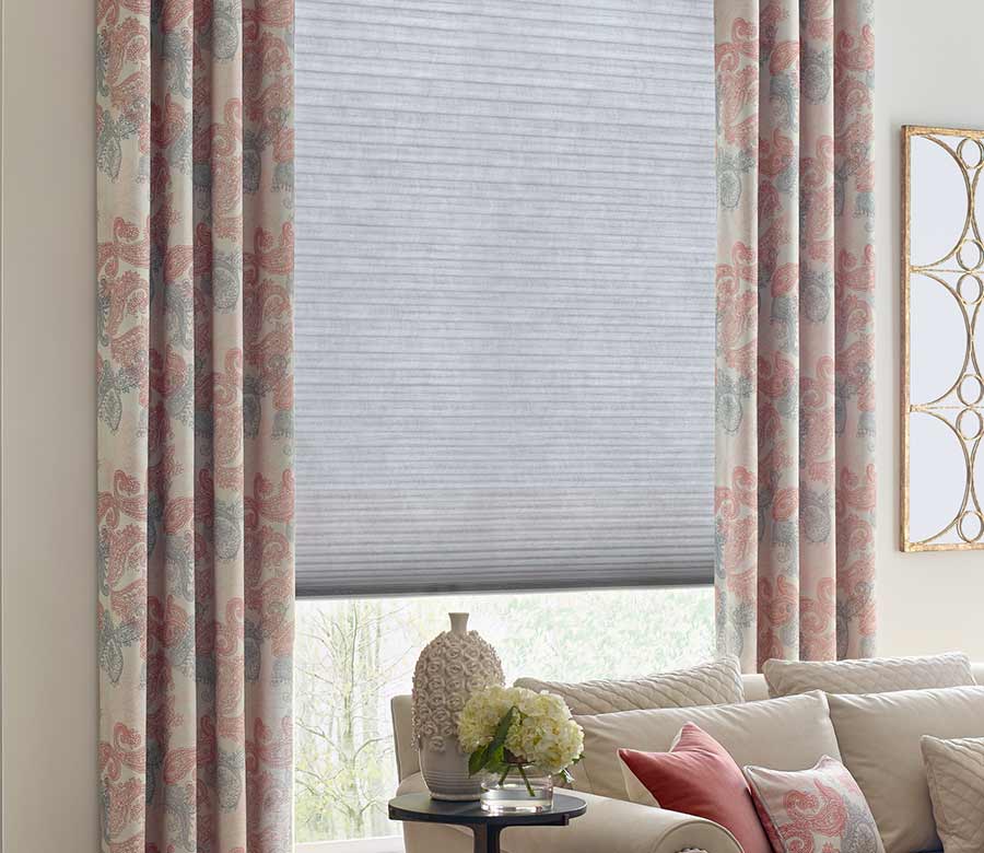green and pink paisley pattern on drapes next to beige couch