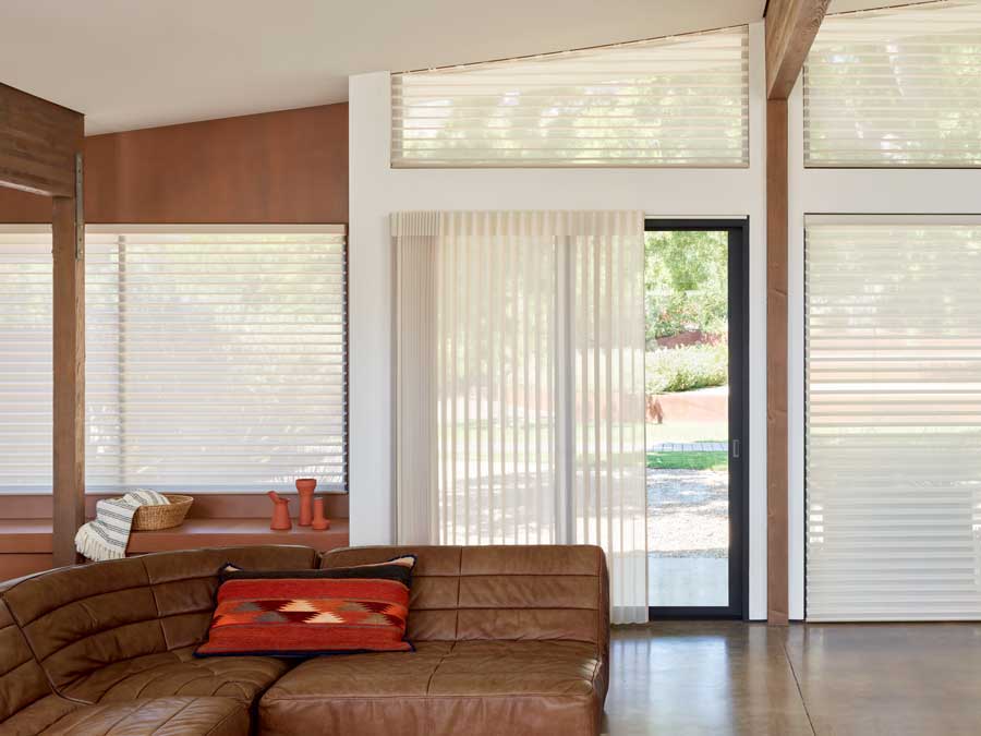 Luminette® Privacy Sheers cover the sliding door; Silhouette® Window Shades cover the windows in a cozy, open floor plan room.