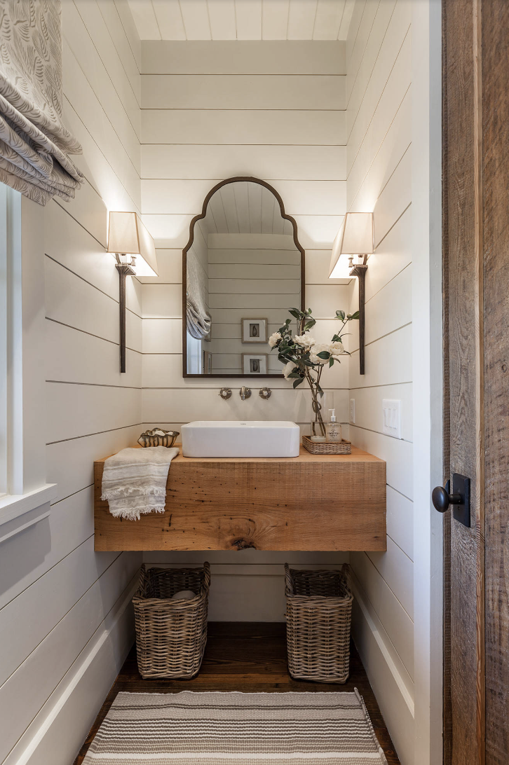 shiplap half bathroom with a mirror over a sink