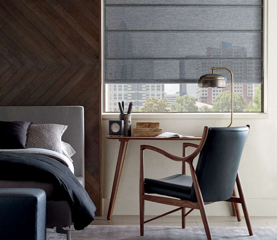 guest bedroom with modern desk, chair, and lamp with gray window treatments