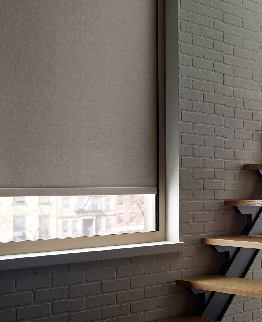 Designer Roller Shades on a windowed wall that holds stairs.