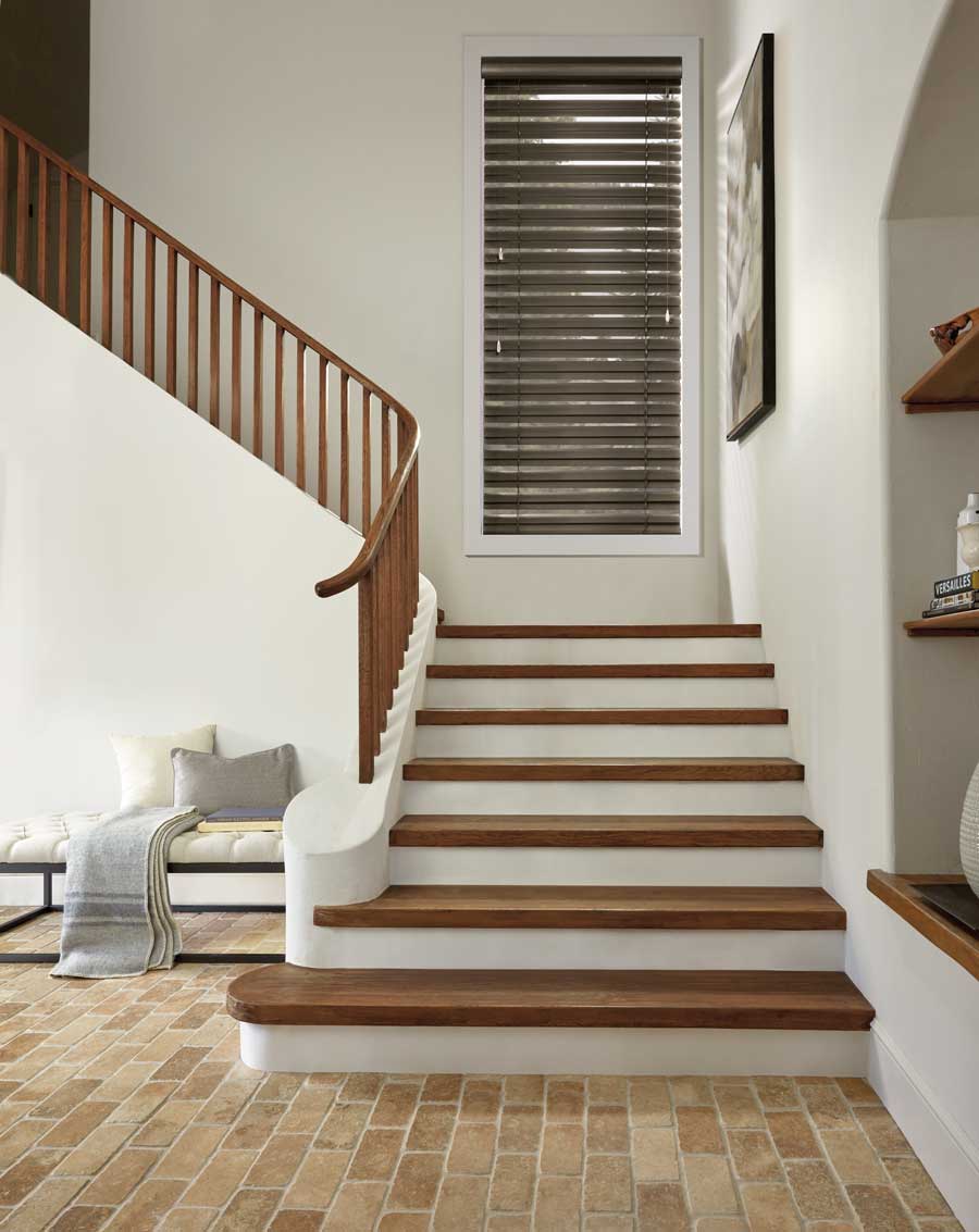 beautiful neutral staircase with a window right above the first landing