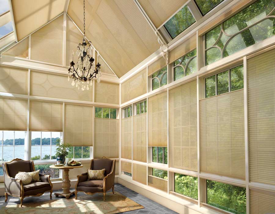 cellular shades on sunroom windows of glass room