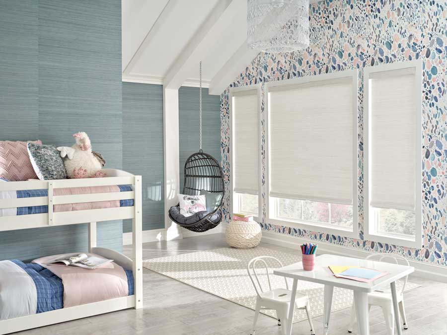 Provenance® Woven Woods in a bright kids bedroom. To the left are white bunk beds with pink bedspreads. The walls are cool blue with a sold wall and floral blue wallpaper on the other. 