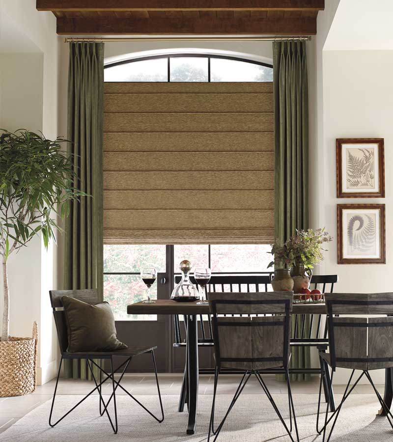 olive green drapery on arched window with beige roman shade in dining area