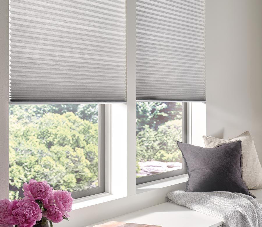 window seat with white honeycomb window shades in bedroom